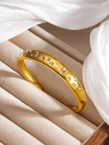 Détail macro du bracelet lune et étoiles en or 18k avec zircons sur satin blanc