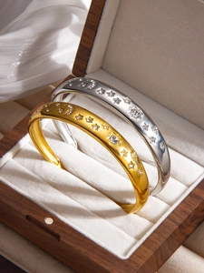 Vue macro des bracelets lune étoile en or 18k et argent dans une boîte à bijoux en bois