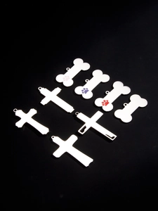 Close-up of polished bone and cross shaped pet ID tags with colorful paw prints