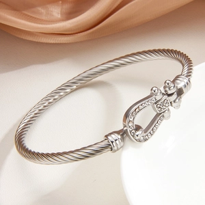 Bracciale a cavo argentato con fibbia a ferro di cavallo e cristalli su sfondo satin