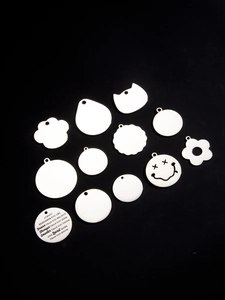Macro detail of diverse white metal pet tags and DIY pendants on black background