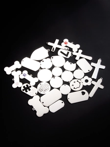 Variety of stainless steel pet tags and pendants with engraved patterns on black background