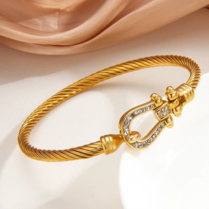 Bracciale a cavo dorato con fibbia a ferro di cavallo in cristallo su piatto elegante