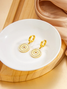Detailed close-up of gold Roman numeral earrings with pavé zircons on white porcelain