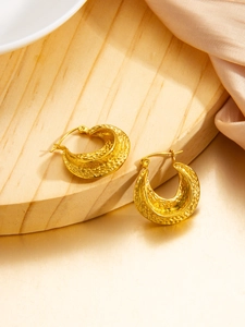 Detail of 18k gold plated lunar hoop earrings with hand-hammered texture on wooden stand