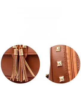 Detail of brown litchi leather backpack featuring gold rivets and twin tassel charms