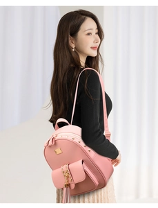 Close-up of pink leather backpack featuring gold rivet accents and a stylish tassel charm
