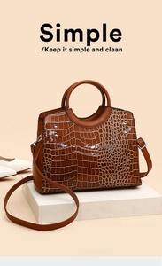 Detailed view of brown crocodile texture leather handbag with silver rivets and handle