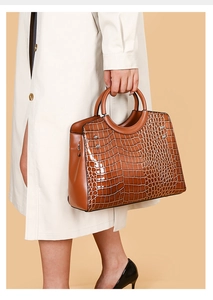 Close-up of brown crocodile embossed faux leather handbag with metallic rivet details