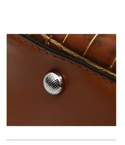 Detail of brown leather bag base with embossed texture and protective silver metal feet