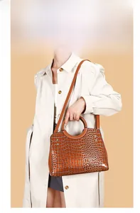Brown crocodile texture handbag styled with a cream trench coat on a model