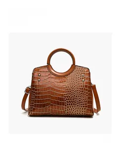 Detail of brown crocodile pattern shoulder bag with silver studs and metal ring handle