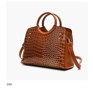 Detail view of brown crocodile embossed pattern and silver studs on the women's handbag