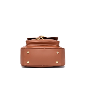 Bottom view of brown leather backpack featuring four gold metal protective studs