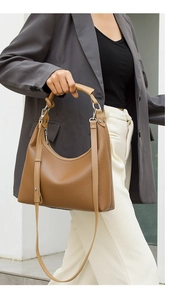 Detailed shot of a brown pebbled leather hobo bag with wide strap on a female model