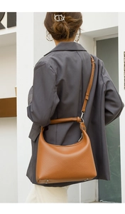 Close-up of brown lychee leather hobo bag with bottom protective metal studs and wide handle