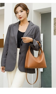 Brown litchi grain leather hobo bag worn with a charcoal blazer in a modern street setting
