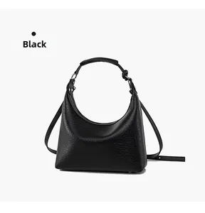 Detail of black pebbled leather texture on minimalist hobo bucket bag with zipper