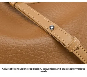 Detail of adjustable shoulder strap with silver rivets on caramel leather bucket bag