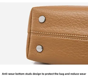 Detail of brown leather bag base with silver metal protective studs and fine stitching