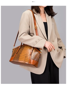 Brown crocodile pattern shoulder bag on model with adjustable strap and gold hardware