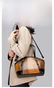 Detail of crocodile embossed faux leather bag with gold hardware and shoulder strap
