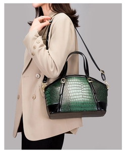 Detail of green and black crocodile embossed handbag with luxury gold hardware