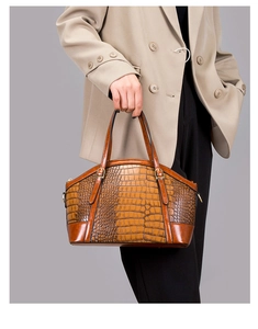 Detail of vintage brown crocodile pattern handbag with elegant gold hardware handle