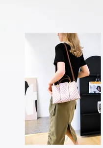Dettaglio della borsa a quadri rosa indossata a spalla con tracolla in pelle marrone