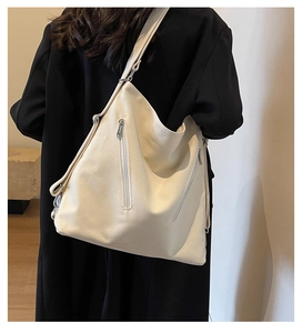 Detail showing cream canvas backpack strap and adjustable silver zippers on large tote