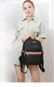 Detail of black oxford backpack featuring gold zippers and rivet quilted front pocket