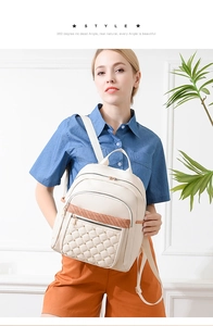 Detail of beige quilted backpack with gold rivets and woven strap shown on a model