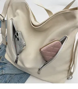 Detail of canvas bag with two front zipper pockets showing phone and wallet storage