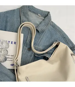 Detail of adjustable strap and silver zipper on a beige canvas tote bag with book props