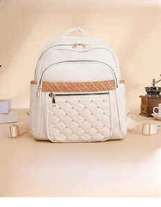 Detail of quilted beige Oxford fabric backpack with gold studs and woven strap accents