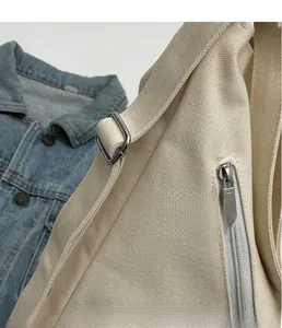 Detail of sturdy beige canvas texture with silver metal buckle and zipper on shoulder bag