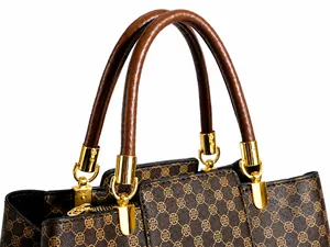 Dettaglio della borsa vintage con manici in pelle marrone e finiture in metallo dorato