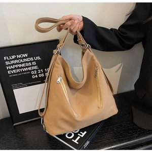 Detail of khaki canvas tote bag featuring dual vertical silver zippers and wide shoulder strap