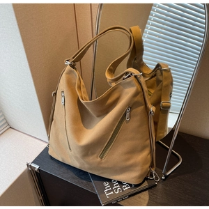 Close-up of khaki canvas tote bag with front zipper pockets and adjustable wide strap