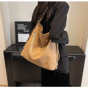 Detail view of khaki canvas shoulder bag with multiple functional exterior metal zippers