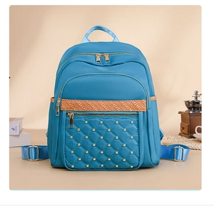 Detail view of light blue oxford backpack with quilted diamond pattern and gold rivets