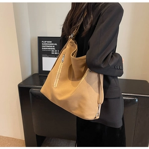 Close-up of khaki canvas shoulder bag showing adjustable strap and side zipper pocket