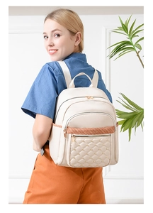 Detail of quilted beige nylon backpack with gold studs and woven strap on model