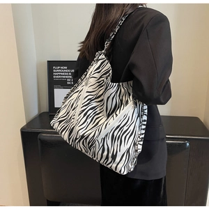 Detail of zebra pattern canvas tote with silver zipper and chain strap on a model