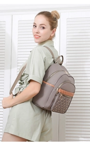 Detail of taupe oxford backpack featuring quilted pattern with golden rivets and sequins