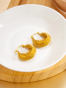 Detailed view of hammered texture on golden C-shaped stainless steel hoop earrings