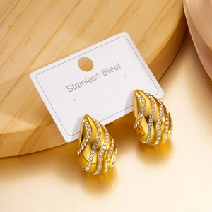 Détail de boucles d'oreilles gouttes dorées avec strass brillants sur carte blanche