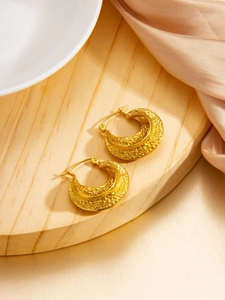 Detail of 18k gold plated chunky hoop earrings with hammered texture on silk fabric