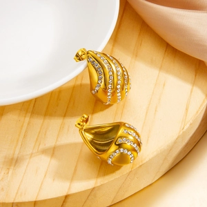 Détail de boucles d'oreilles goutte dorées avec micro-strass brillants sur soie