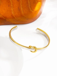 Detail of two-tone gold and silver knot cuff bracelet in polished stainless steel